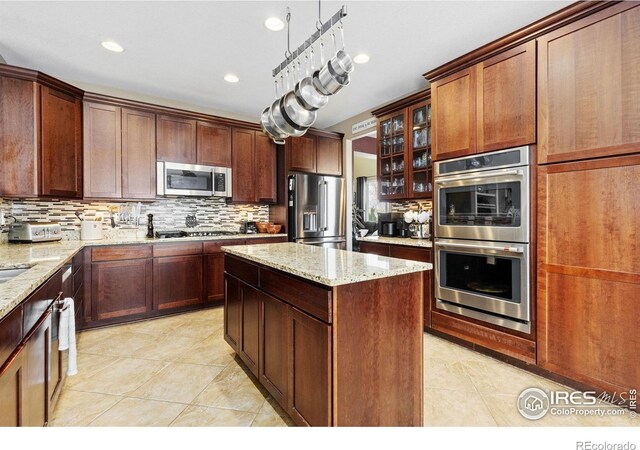 kitchen with glass insert cabinets, backsplash, light tile patterned floors, and stainless steel appliances