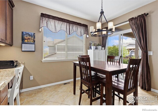 dining area featuring baseboards, light tile patterned floors, and a notable chandelier