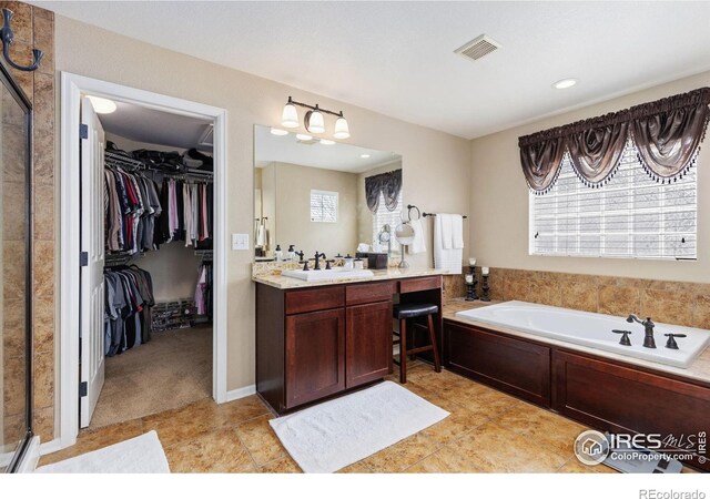 bathroom featuring visible vents, vanity, a walk in closet, tile patterned floors, and a bath