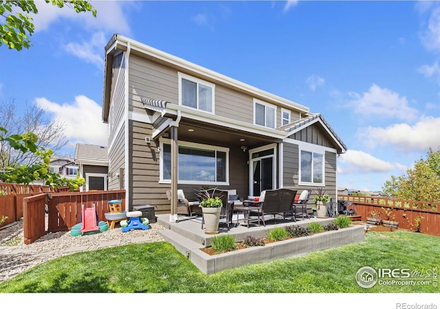 rear view of property featuring a yard, an outdoor hangout area, a fenced backyard, and a patio area