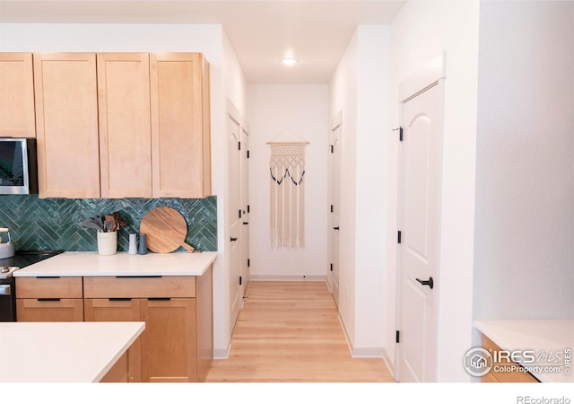 4424 Haymill Ct, Timnath, CO 80547 - kitchen with stainless steel microwave, light brown cabinets, light wood-style floors, light countertops, and decorative backsplash