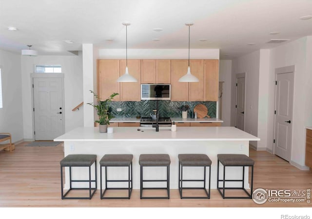 4424 Haymill Ct, Timnath, CO 80547 - kitchen with light brown cabinets, backsplash, light countertops, light wood-type flooring, and a breakfast bar area