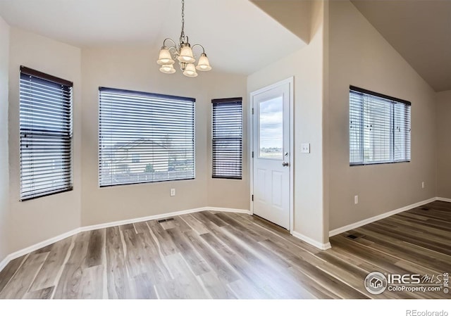 8301 W 18th Street Rd, Greeley, CO 80634 - unfurnished dining area featuring a chandelier, vaulted ceiling, wood finished floors, and baseboards