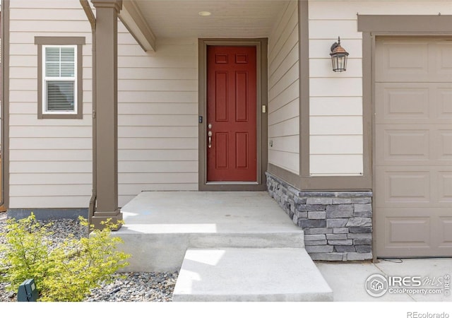 entrance to property featuring stone siding and a garage