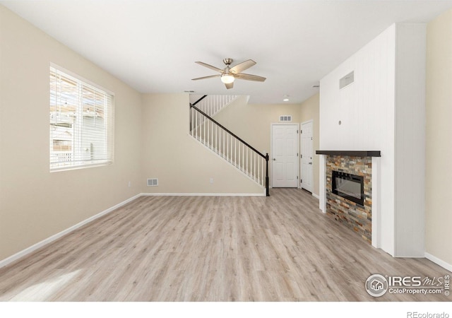 unfurnished living room featuring ceiling fan, light wood-type flooring, stairs, and visible vents