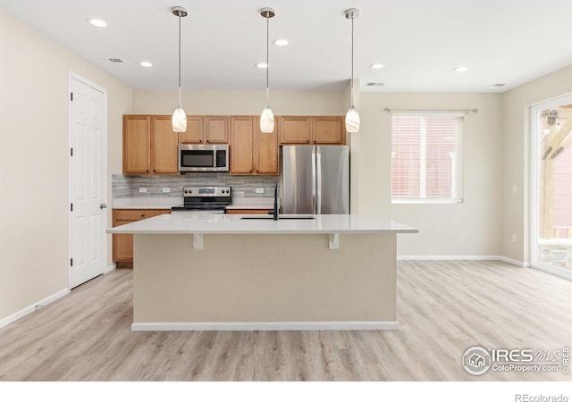 kitchen featuring backsplash, light wood-type flooring, a sink, light countertops, and stainless steel appliances