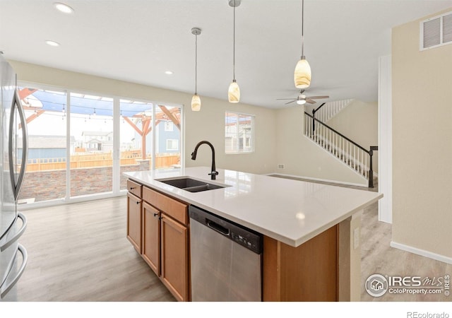 kitchen with visible vents, light wood-type flooring, a sink, decorative light fixtures, and stainless steel appliances