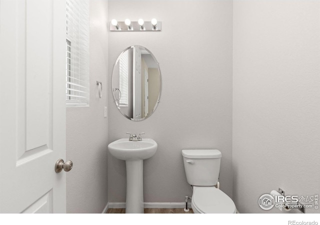 bathroom featuring toilet, baseboards, and a sink