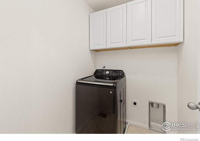 clothes washing area featuring baseboards, cabinet space, and washer / clothes dryer