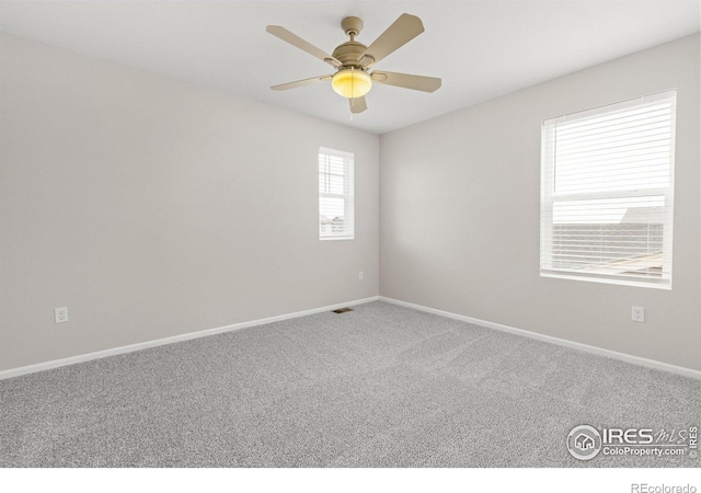 carpeted empty room with baseboards, ceiling fan, and visible vents