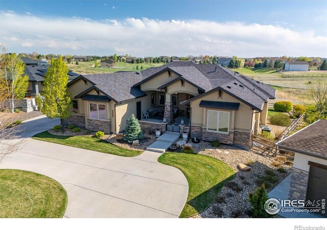 5751 Last Pointe Dr, Windsor, CO 80550 - view of front facade with stone siding, stucco siding, covered porch, and a shingled roof