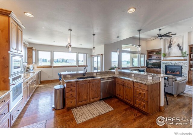 5751 Last Pointe Dr, Windsor, CO 80550 - kitchen featuring stainless steel appliances, a sink, dark wood-type flooring, brown cabinetry, and recessed lighting