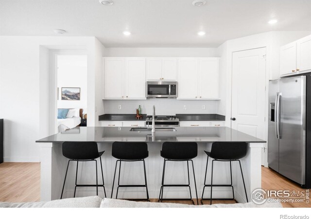 840 Clover Loop, Lafayette, CO 80026 - kitchen with a sink, white cabinetry, appliances with stainless steel finishes, and a breakfast bar