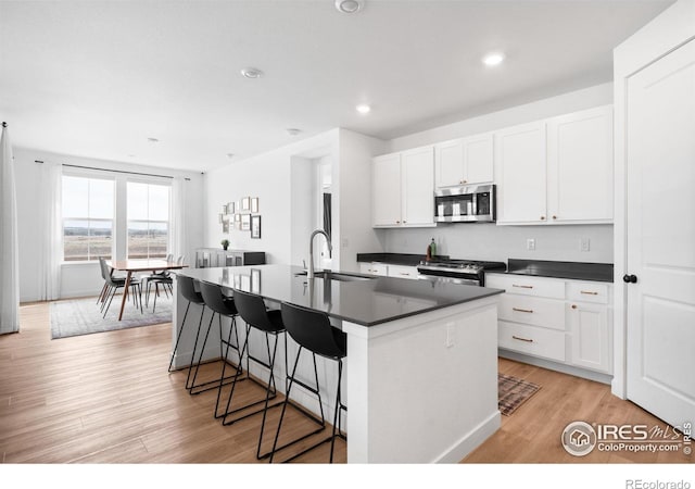 840 Clover Loop, Lafayette, CO 80026 - kitchen with dark countertops, appliances with stainless steel finishes, a breakfast bar, and a center island with sink