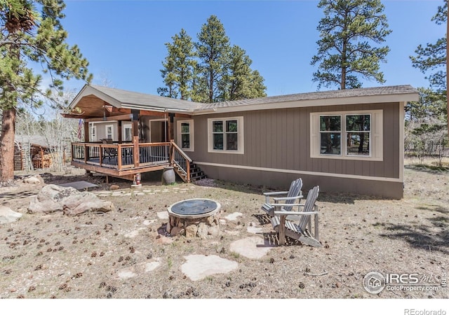 back of property featuring a fire pit and a deck