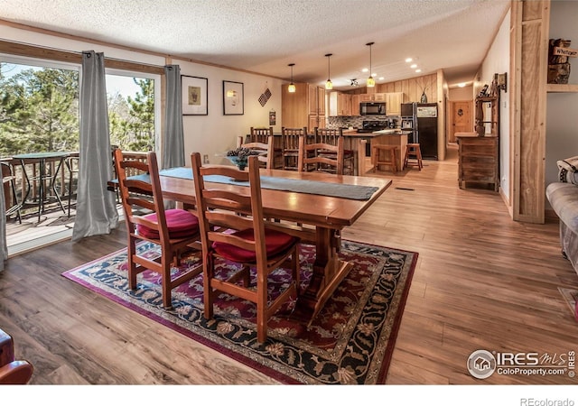dining area with a textured ceiling and light wood-type flooring