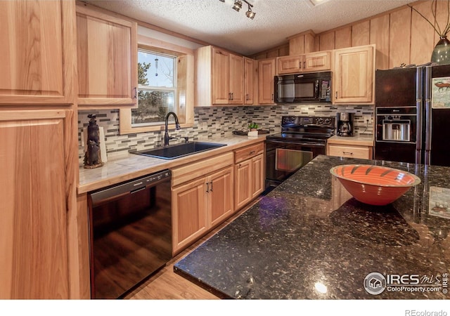 kitchen with backsplash, light brown cabinetry, a sink, and black appliances