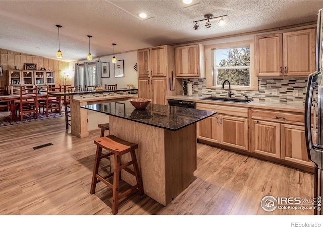 kitchen with a textured ceiling, a center island, light wood-type flooring, a sink, and a peninsula