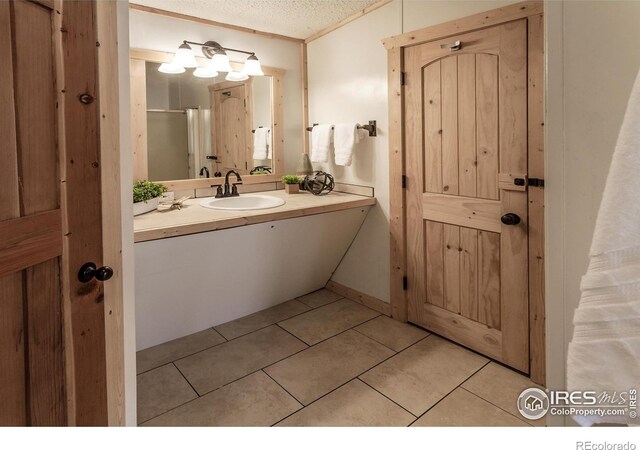 bathroom with a textured ceiling, a shower with door, tile patterned flooring, and vanity
