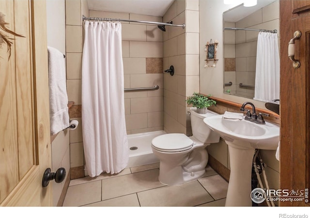 bathroom with tile patterned flooring, a tile shower, and toilet