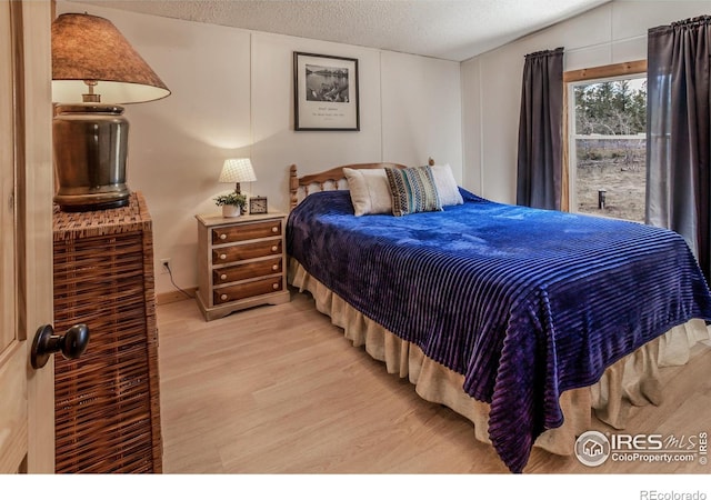 bedroom with light wood finished floors and a textured ceiling
