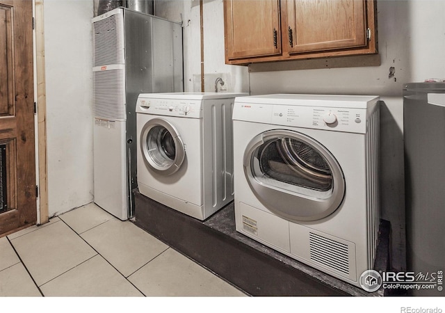 laundry area featuring a heating unit, cabinet space, light tile patterned flooring, and washer and dryer