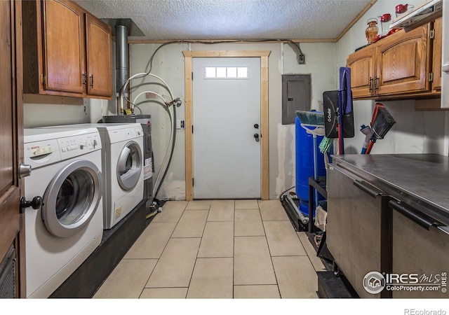 laundry area featuring a textured ceiling, electric panel, washing machine and clothes dryer, cabinet space, and light tile patterned floors