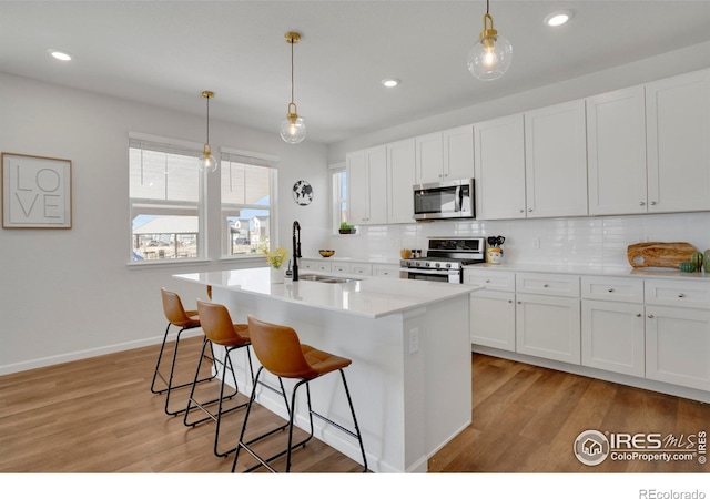 1312 Loraine Cir S, Lafayette, CO 80026 - kitchen with decorative backsplash, a kitchen bar, white cabinets, a sink, and appliances with stainless steel finishes