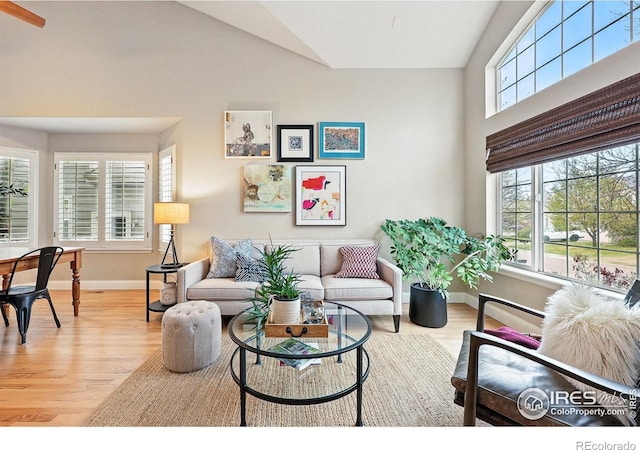 living room with baseboards, light wood-style flooring, and lofted ceiling