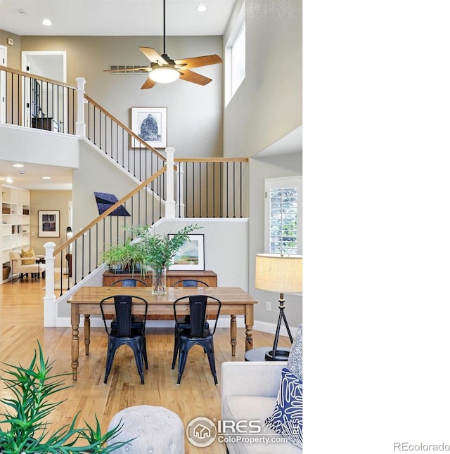 dining space featuring a high ceiling, stairs, a ceiling fan, recessed lighting, and wood finished floors