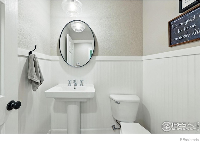 bathroom with a wainscoted wall and toilet
