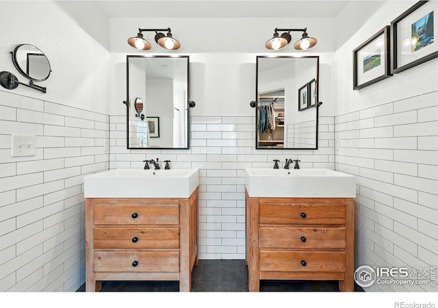 bathroom with a sink, tile walls, and two vanities