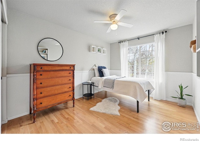 bedroom with a textured ceiling, ceiling fan, and wood finished floors