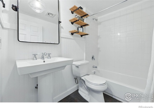 bathroom featuring toilet, tile patterned floors, baseboards, and shower / bath combo