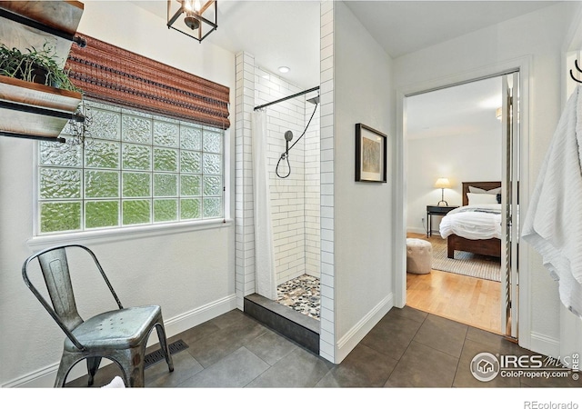 bathroom featuring baseboards, connected bathroom, tile patterned floors, and tiled shower