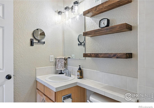 bathroom with vanity, a textured wall, and toilet