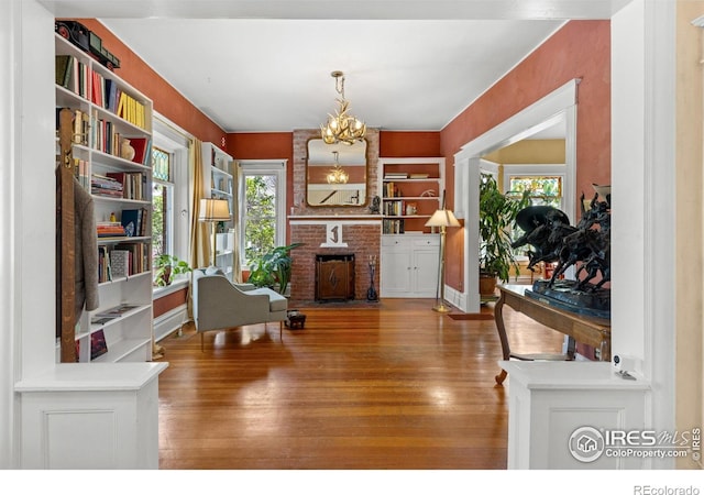 838 University Ave, Boulder, CO 80302 - sitting room featuring an inviting chandelier, plenty of natural light, a brick fireplace, and wood finished floors