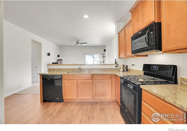 kitchen with light wood-style floors, a peninsula, ceiling fan, and black appliances