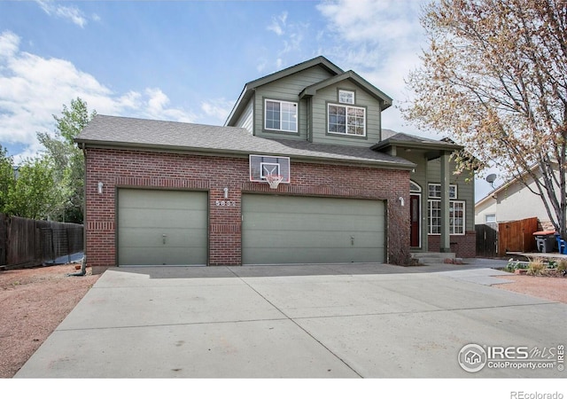 traditional home featuring concrete driveway, brick siding, an attached garage, and fence
