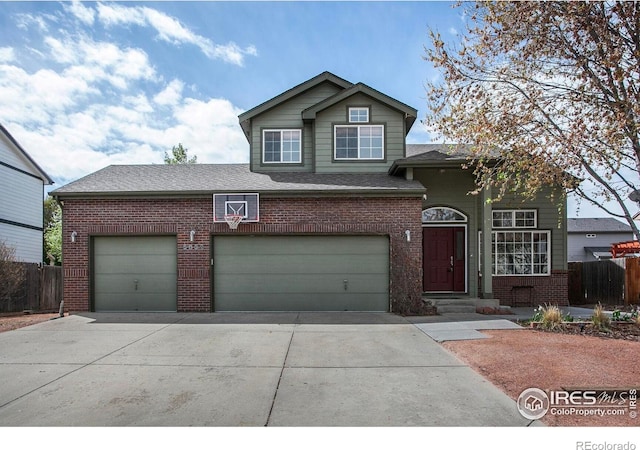traditional-style home featuring concrete driveway, brick siding, fence, and a shingled roof