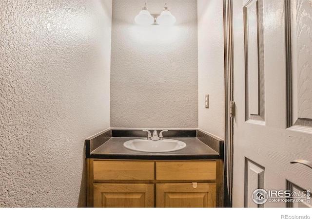 bathroom featuring vanity and a textured wall