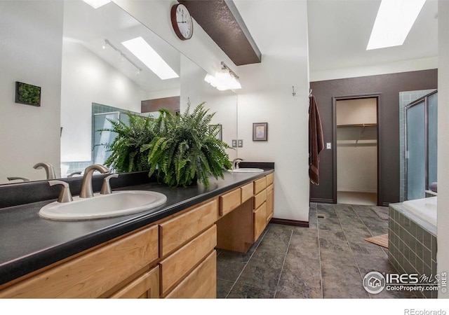 full bath with double vanity, a sink, a shower with shower door, and a skylight