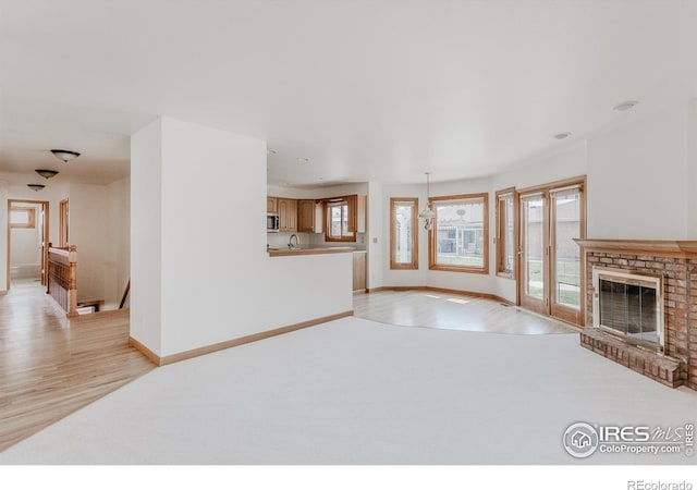 1609 Sherman Way, Longmont, CO 80501 - unfurnished living room featuring a fireplace, a wealth of natural light, and light wood-style floors