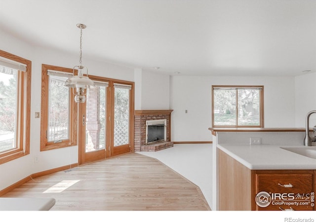 1609 Sherman Way, Longmont, CO 80501 - kitchen featuring a sink, a brick fireplace, decorative light fixtures, baseboards, and light wood-type flooring