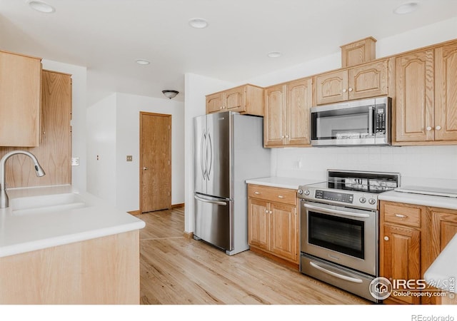 1609 Sherman Way, Longmont, CO 80501 - kitchen featuring a sink, light countertops, light wood finished floors, light brown cabinets, and stainless steel appliances