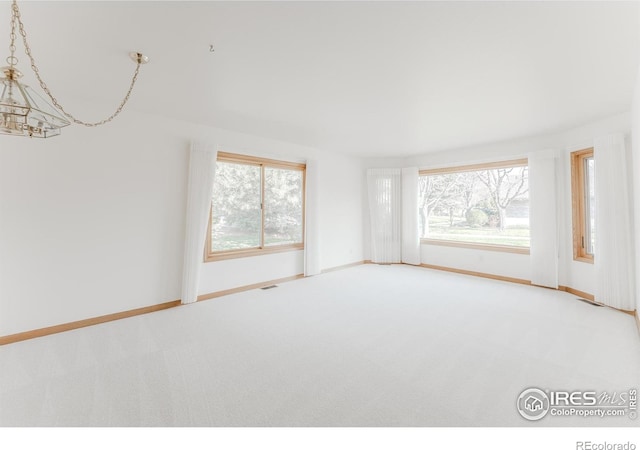 1609 Sherman Way, Longmont, CO 80501 - carpeted spare room featuring baseboards, a chandelier, and a wealth of natural light