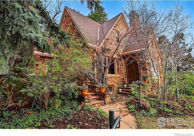 1025 5th St, Boulder, CO 80302 - view of front of house featuring a shingled roof, stone siding, and a chimney