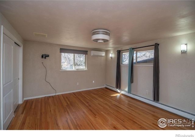 2605 Crabapple Ct, Golden, CO 80401 - empty room featuring visible vents, a wall mounted AC, baseboard heating, wood finished floors, and baseboards