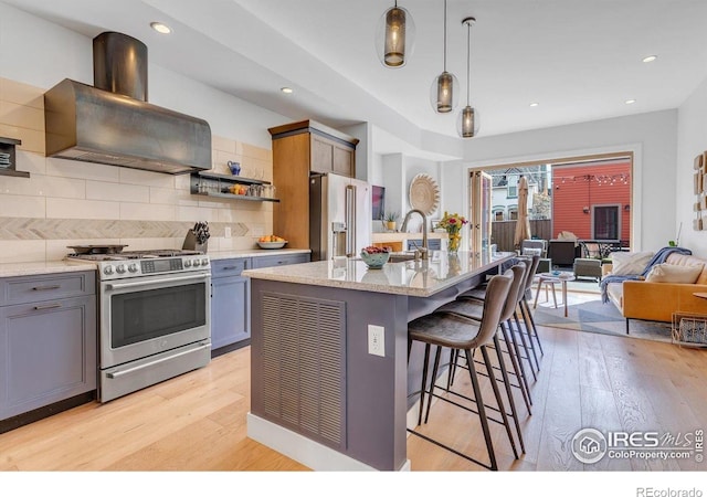 2890 Curtis St, Denver, CO 80205 - kitchen with stainless steel appliances, ventilation hood, light wood finished floors, light stone countertops, and tasteful backsplash