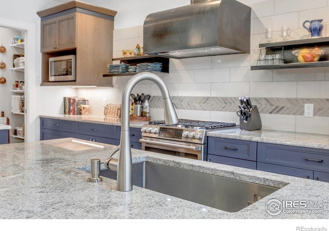 2890 Curtis St, Denver, CO 80205 - kitchen with wall chimney exhaust hood, light stone countertops, stainless steel gas range, and backsplash